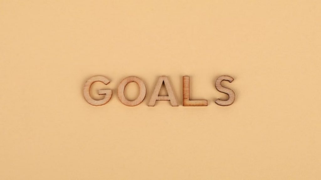 Wooden letters spelling 'GOALS' on a plain background, emphasizing motivation.