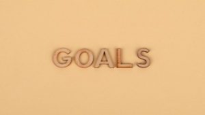 Wooden letters spelling 'GOALS' on a plain background, emphasizing motivation.